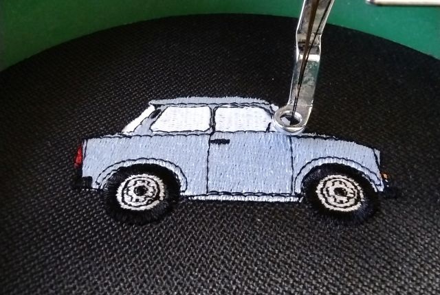 Gesticktes Trabant Auto auf schwarzem Stoff – Maschinenstickerei eines Oldtimers mit feinen Details
